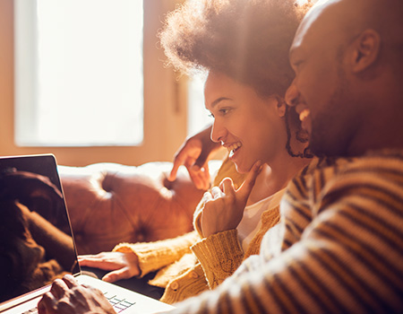 Happy smiling couple looking at a laptop computer