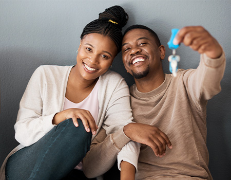 Happy smiling couple holding up a key to a new home